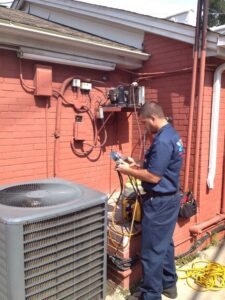 An Icy Hot Heating and Air Conditioning technician checking an outdoor AC unit in Raleigh, NC.