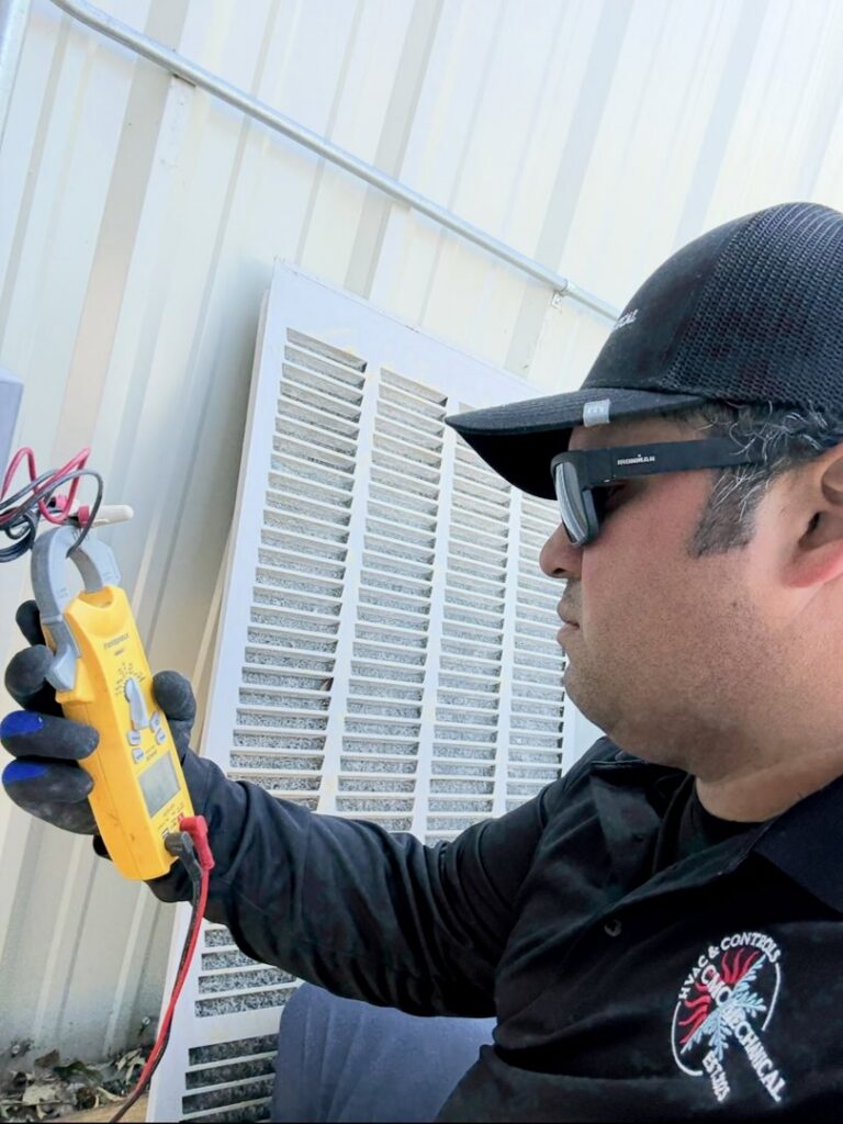 An HVAC technician checking electrical readings with a clamp meter for CMC Mechanical, LLC in Caldwell, ID.