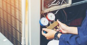 An HVAC technician checking refrigerant gauges on an outdoor unit for Air Works of Alabama LLC in Mobile, AL.