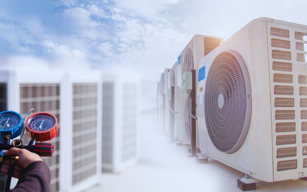 An HVAC technician checking refrigerant gauges with multiple outdoor AC units in the background for Moreau's Heating & AC in Lake Charles, LA.