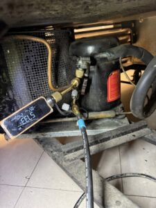 An HVAC technician checking refrigerant levels on an indoor unit compressor for LeoAir, LLC in West Jordan, UT