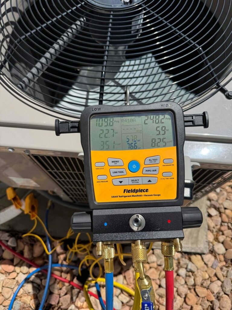 An HVAC technician using a digital manifold gauge to check refrigerant levels on an outdoor AC unit in Orem, UT.