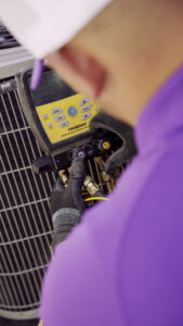 An HVAC technician from CSA HVAC Services checking refrigerant levels on an outdoor AC unit in Orem, UT.