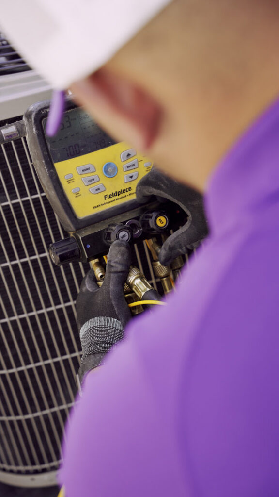 An HVAC technician from CSA HVAC Services checking refrigerant levels on an outdoor AC unit in Orem, UT.