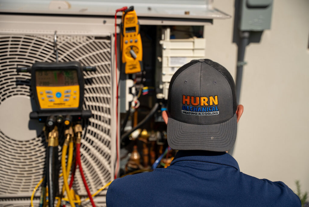 An HVAC technician checking refrigerant levels on an outdoor unit for Hurn Mechanical Heating & Cooling in El Cajon, CA.