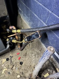 An HVAC technician checking refrigerant levels on an outdoor unit with gauges for LeoAir, LLC in West Jordan, UT