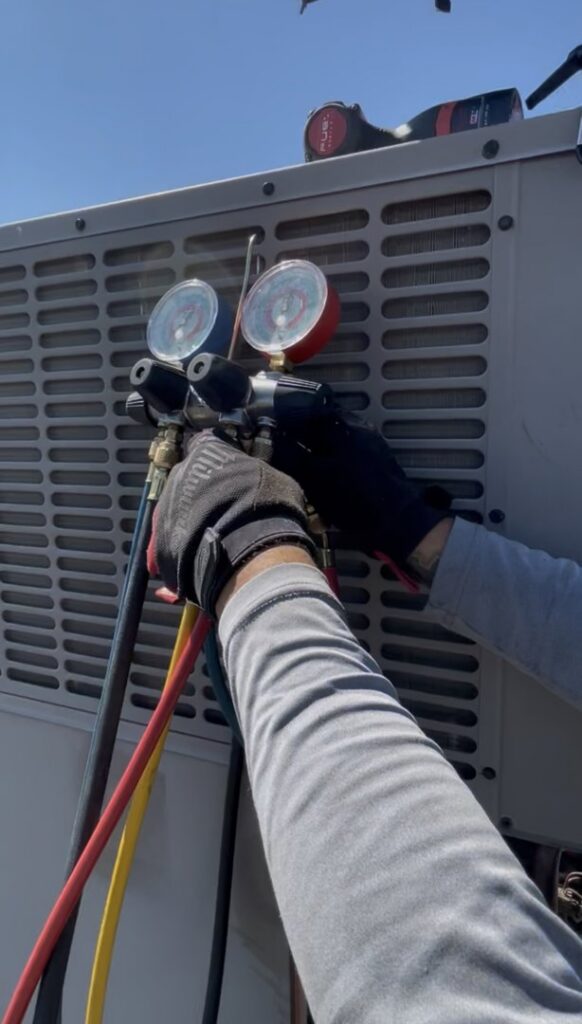 An HVAC technician checking refrigerant levels on an outdoor unit for Sun Devil Heating & Cooling INC in Peoria, AZ.