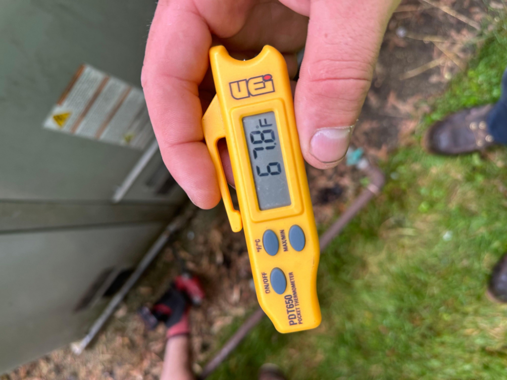 An HVAC technician checking the temperature with a digital thermometer during a service call by Cardinal Repairs in Canton, OH