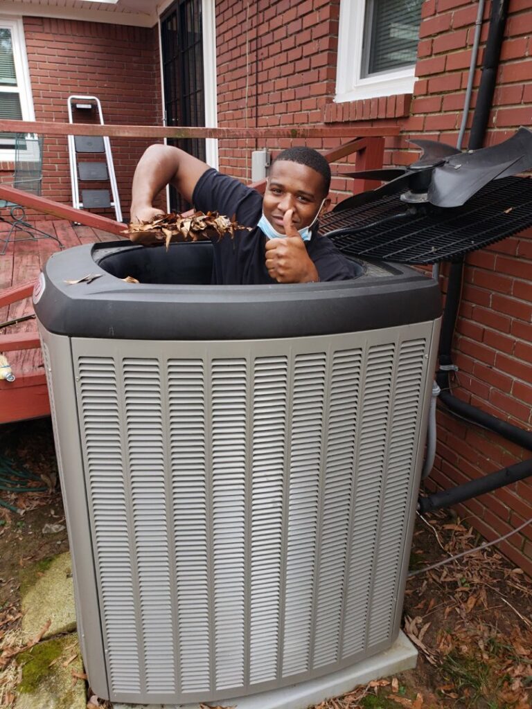 A Service Experts Memphis technician cleaning leaves from an outdoor air conditioning unit in Memphis, TN.