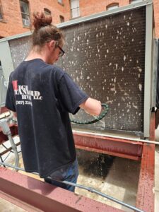 An HVAC technician from High Standard HVAC LLC cleaning the coils of a large commercial unit in Cheyenne, WY.