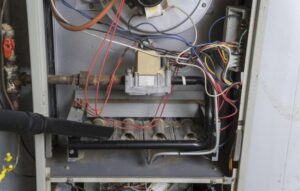 An HVAC technician cleaning the inside of a furnace or heating unit for General Air Conditioning Service Corp in Greenville, SC.