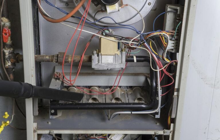 An HVAC technician cleaning the inside of a furnace or heating unit for General Air Conditioning Service Corp in Greenville, SC.