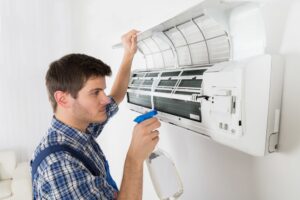 An HVAC technician cleaning an indoor mini-split air conditioning unit for Airtechservicesohio.com in Columbus, OH