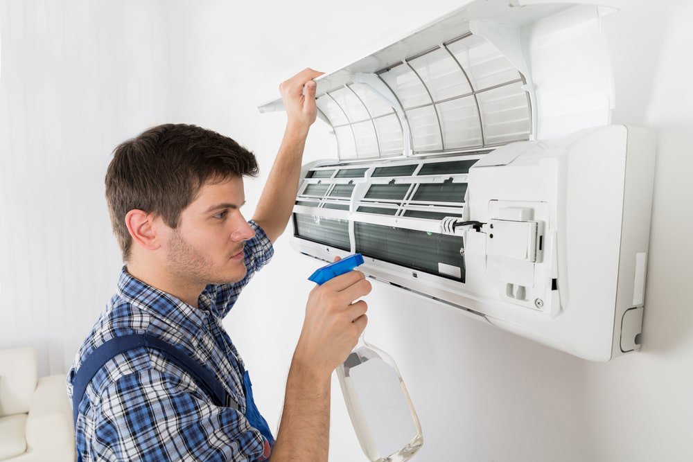 An HVAC technician cleaning an indoor mini-split air conditioning unit for Airtechservicesohio.com in Columbus, OH