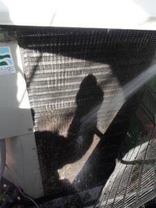 An HVAC technician from Go West A/C & Heating cleaning an outdoor AC coil in Fort Worth, TX.