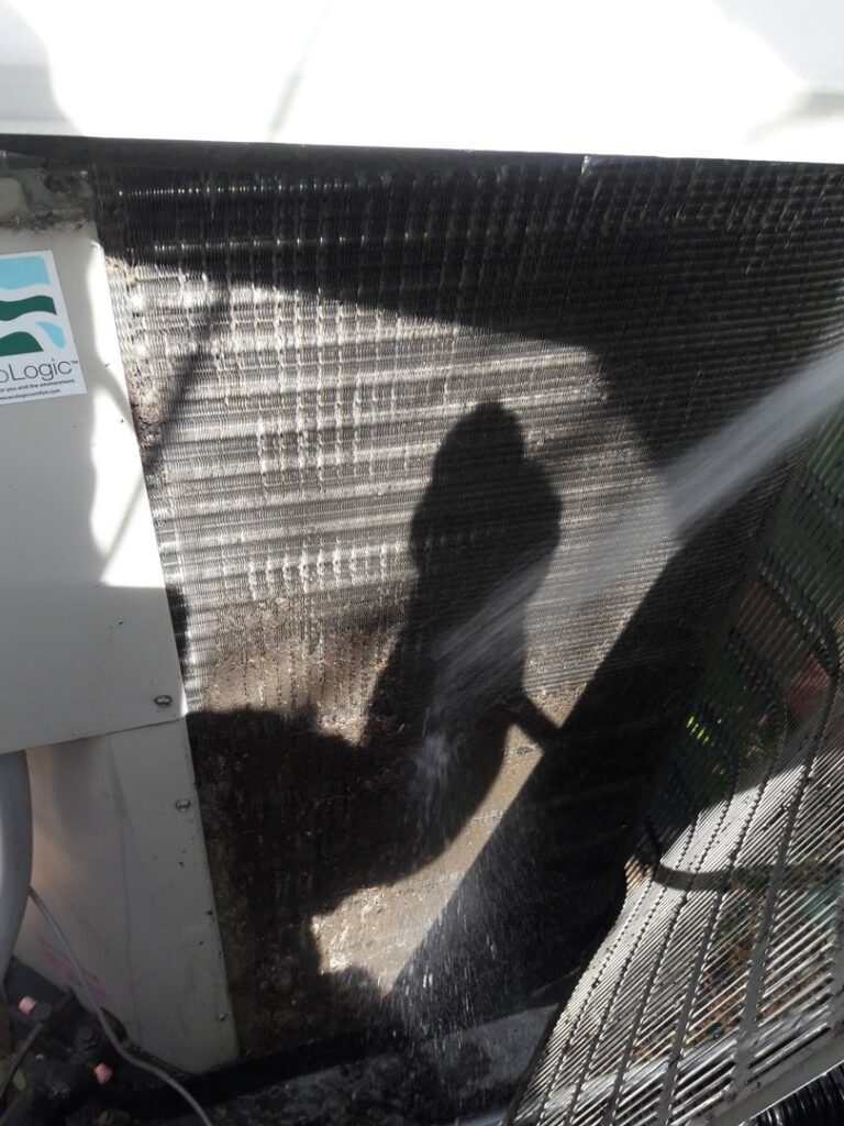 An HVAC technician from Go West A/C & Heating cleaning an outdoor AC coil in Fort Worth, TX.