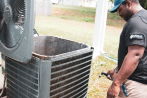 An HVAC technician from Nashville Solutions cleaning an outdoor air conditioning unit in Nashville, TN
