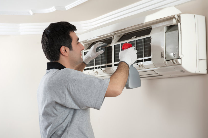 An HVAC technician cleaning an indoor split air conditioning unit for M&S Heating and Air Conditioning in Mechanicsville, MD