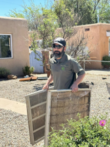 An HVAC technician cleaning a dirty swamp cooler pad for Desert Sage Heating and Cooling in Albuquerque, NM.