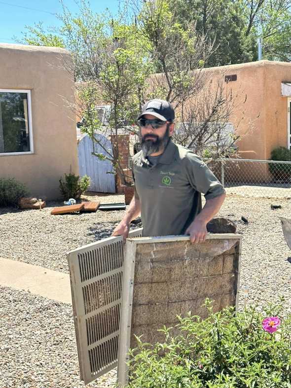 An HVAC technician cleaning a dirty swamp cooler pad for Desert Sage Heating and Cooling in Albuquerque, NM.