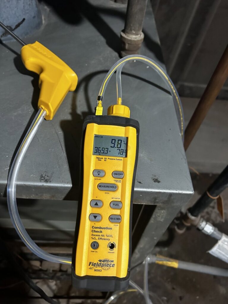 An HVAC technician performing a combustion analysis on a furnace with a Fieldpiece analyzer for Waymaker HVAC LLC in Colorado Springs, CO.