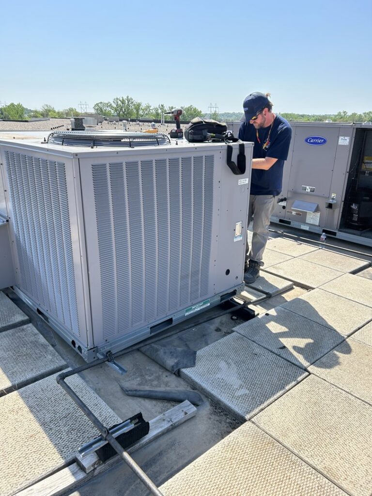An HVAC technician servicing a commercial rooftop unit for Sandys Heating & Air in Papillion, NE.