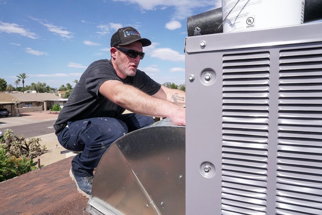 An HVAC technician connecting ductwork to a rooftop unit for Diamond AC and Heating in Phoenix, AZ.