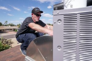 An HVAC technician connecting ductwork to a rooftop unit for Diamond AC and Heating in Phoenix, AZ.