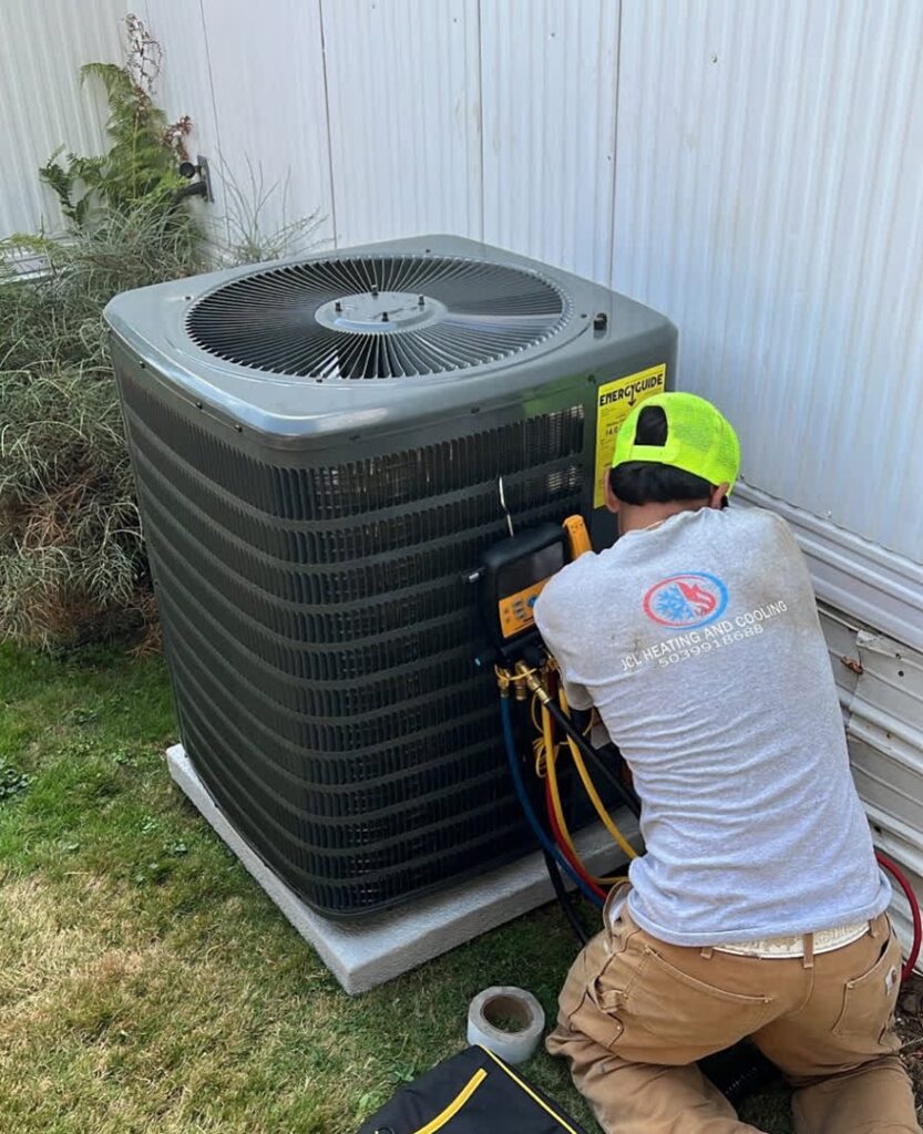 An HVAC technician from JCL Heating and Cooling LLC connecting gauges to an outdoor AC unit in Gresham, OR.