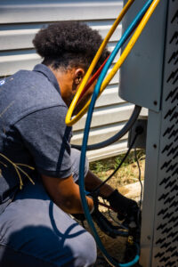 An HVAC technician from Cool Guys Heating & Air LLC connecting gauges to an outdoor AC unit in North Little Rock, AR.
