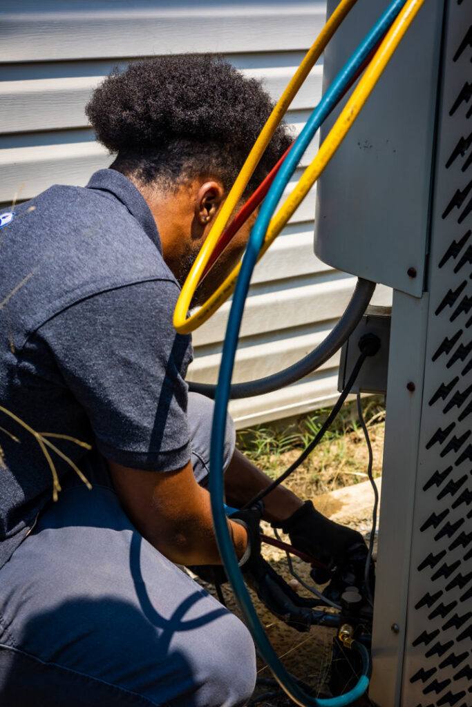 An HVAC technician from Cool Guys Heating & Air LLC connecting gauges to an outdoor AC unit in North Little Rock, AR.