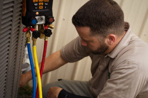 An HVAC technician from Seven Level Services Inc in Cape Coral, FL, connecting refrigerant gauges to an outdoor AC unit.