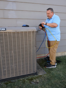 An HVAC technician connecting refrigerant gauges to an outdoor AC unit for Wright Way Air in Streamwood, IL