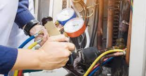 An HVAC technician connecting manifold gauges to an HVAC unit at AC Service Tech Inc in Cedar Rapids, IA.