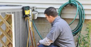 An HVAC technician connecting refrigerant gauges to an outdoor AC unit for Glendale HVAC in Glendale, AZ