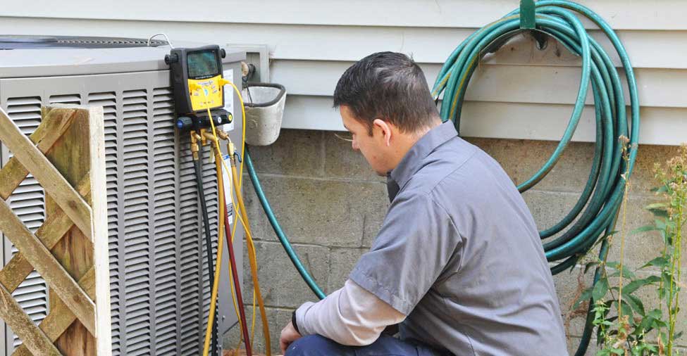 An HVAC technician connecting refrigerant gauges to an outdoor AC unit for Glendale HVAC in Glendale, AZ
