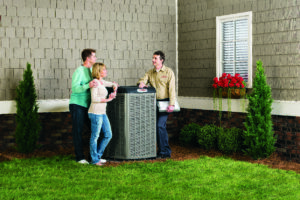 An HVAC technician consulting with customers next to an AC unit for Larry's Heating and Cooling, Inc. in Yankton, SD.