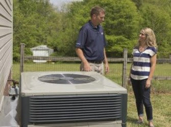 An HVAC technician consulting with a customer next to an outdoor unit from Comfort Zone of the Carolinas in Rock Hill, SC.