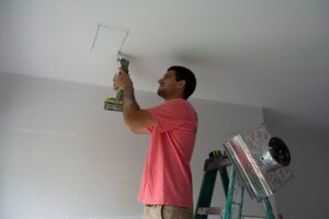 An HVAC technician from Coral Air Conditioning cutting a ceiling opening for a new vent installation in Cape Coral, FL.