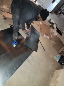 An HVAC technician cutting sheet metal for ductwork installation at a job site for Family First Heating and Cooling Repair LLC in Toledo, OH.