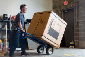 An HVAC technician delivering a new air conditioning unit on a dolly for installation by Calloway & Sons A/C And Heating in New Orleans, LA.