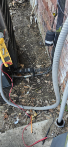 An HVAC technician using a multimeter to diagnose an outdoor AC unit at Anubis Mechanical in Goose Creek, SC.