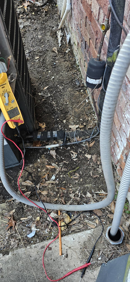 An HVAC technician using a multimeter to diagnose an outdoor AC unit at Anubis Mechanical in Goose Creek, SC.