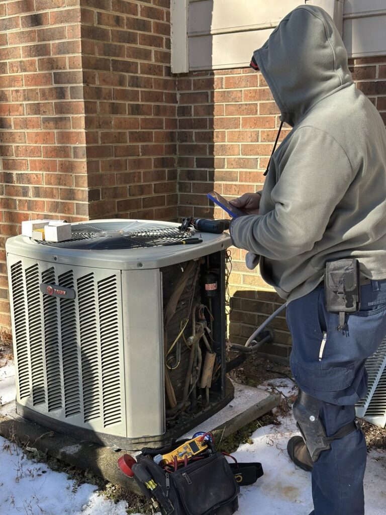 An Icy Hot Heating and Air Conditioning technician diagnosing an outdoor AC unit in Raleigh, NC.