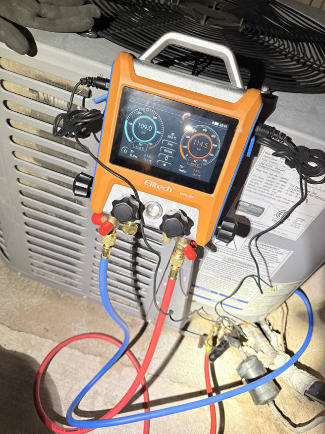 An HVAC technician uses a digital manifold gauge to diagnose an outdoor AC unit at NM Heating and Air in Albuquerque, NM.