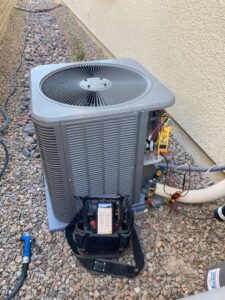 An HVAC technician diagnosing an outdoor air conditioning unit with professional tools for Sahara Air Conditioning & Heating in Las Vegas, NV