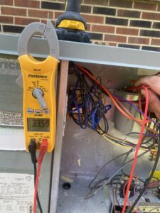 An HVAC technician from Triune Air diagnosing an outdoor AC unit with a multimeter in Smithville, TN.