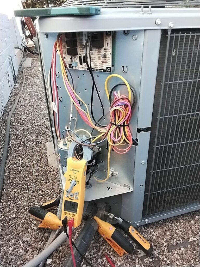 An HVAC technician diagnosing an outdoor AC unit with a multimeter for Heating & Air Paramedics - Tucson in Tucson, AZ.