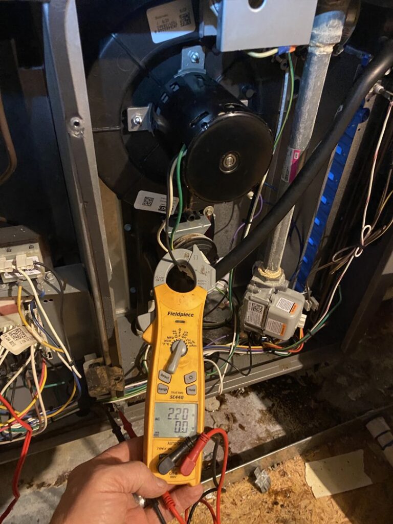 An HVAC technician using a multimeter to diagnose an air handler unit by Reasonable Air, LLC in Summerville, SC.