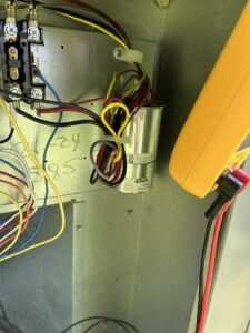 An HVAC technician from Bob Woodall Air Care Systems diagnosing a capacitor with a multimeter in Dothan, AL.